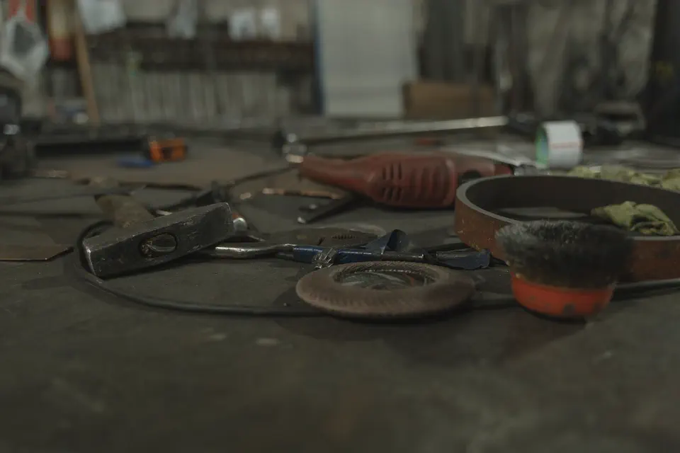 Établi d'atelier couvert d'outils à main et de pièces en cours.