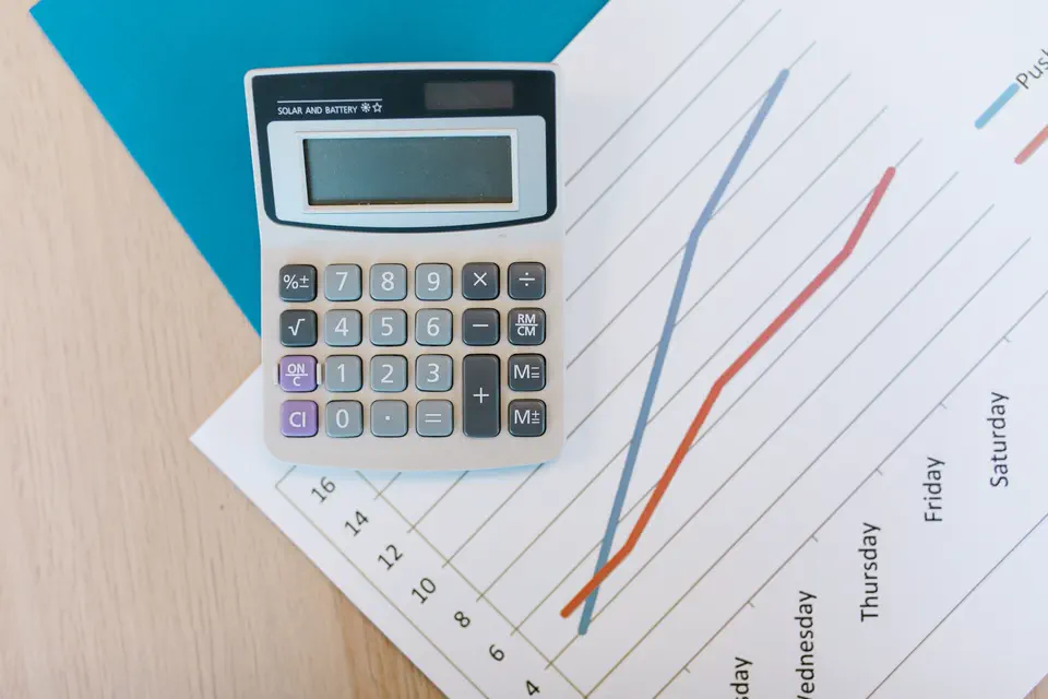 Documents financiers, graphiques et calculatrice sur un bureau.