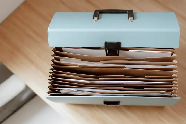 Portefeuille de dossiers et de documents ouverts sur un bureau.