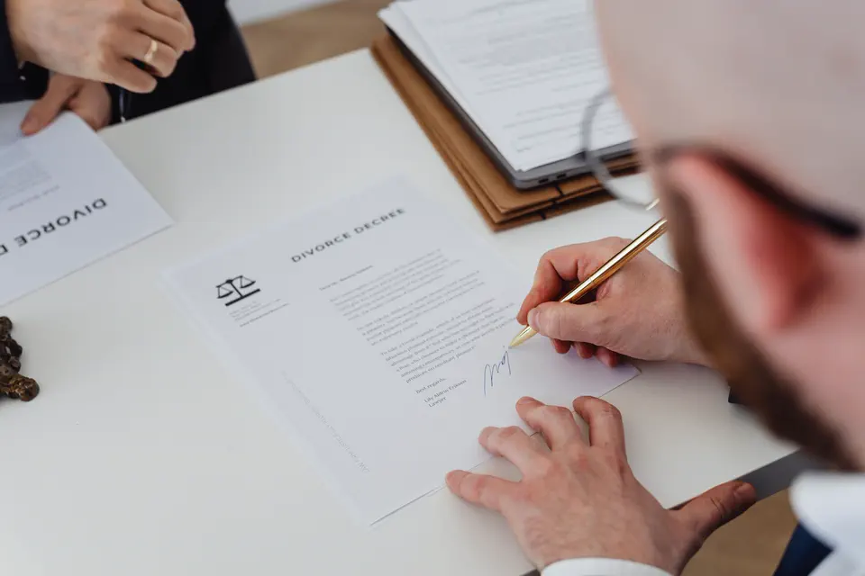 Signature d'un contrat devant des documents posés sur un bureau.